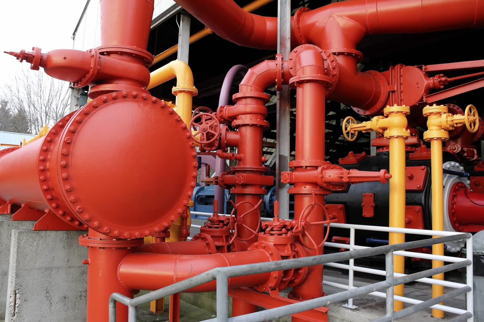 Rot und gelb beschichtete Rohrleitungen und Armaturen einer Industrieanlage